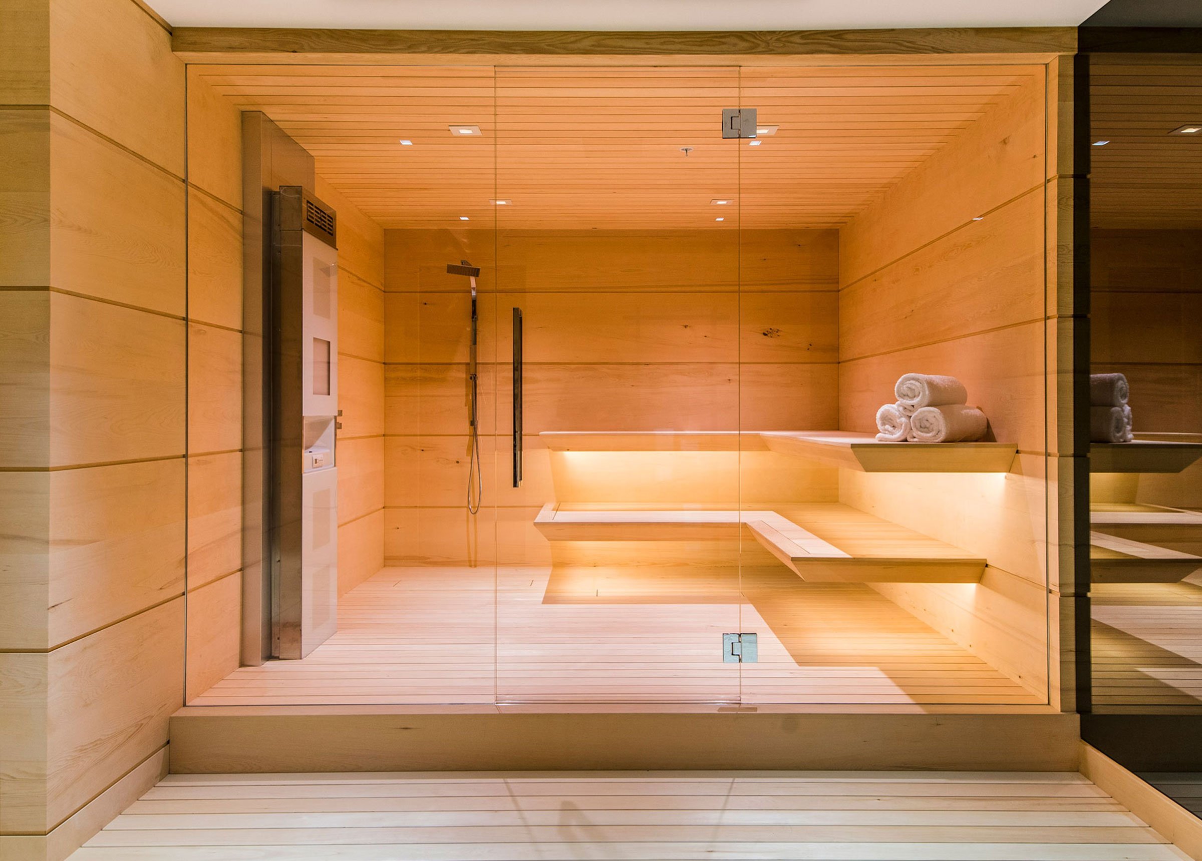 A home sauna with light wood lit with warm white light.